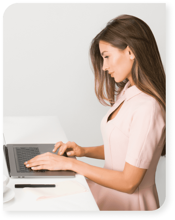 Mujer con vestido rosa pastel y una laptop